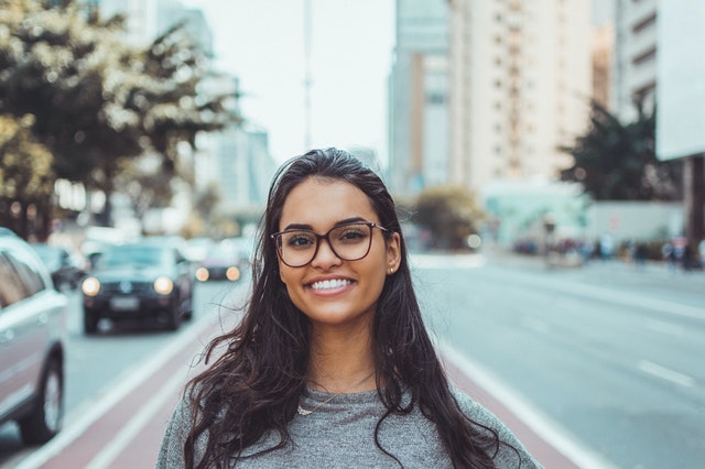 Usmiata žena v okuliaroch stojí na ceste