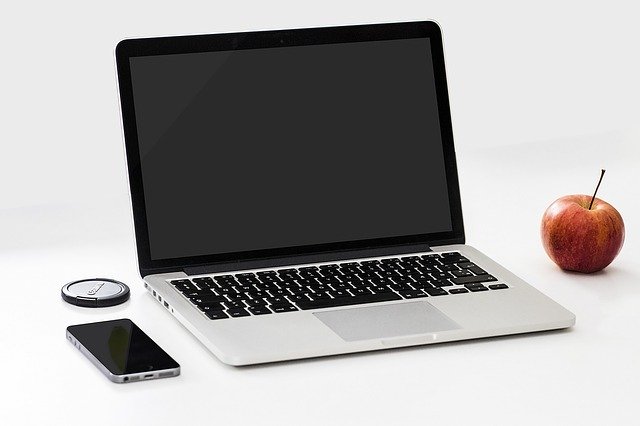 Notebook, jablko a mobil na bielom podklade